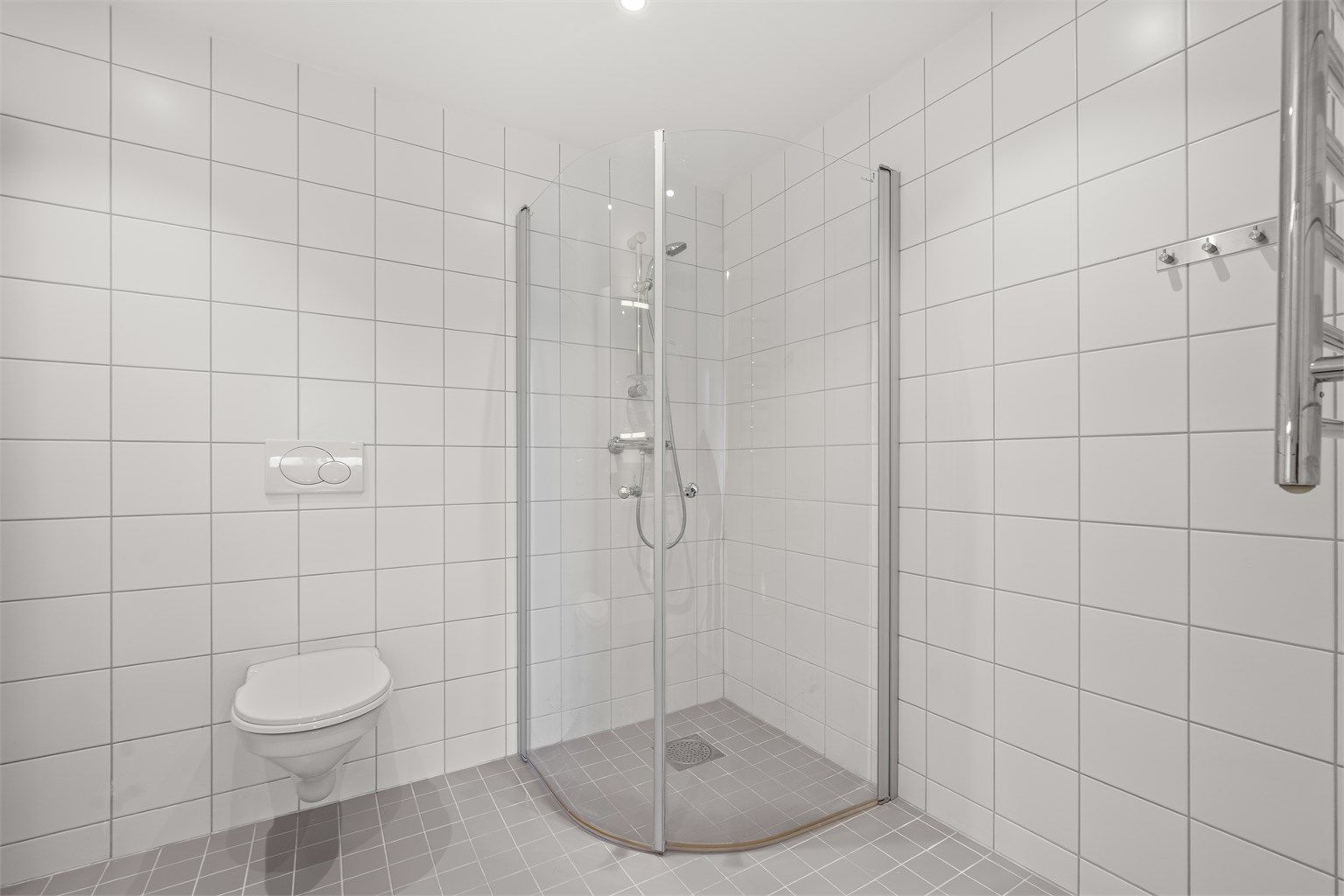 Dusjhjørne med svingbare glassdører og innfelte downlights i himlingen.