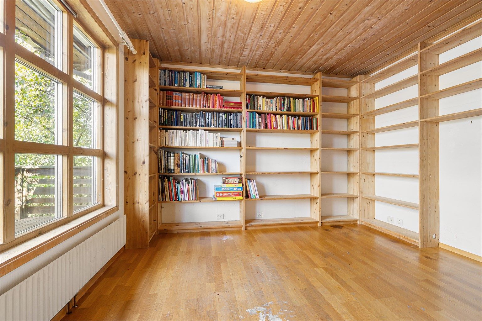 Biblioteket med plassbygde bokhyller gir en rolig sone for arbeid eller lesing.