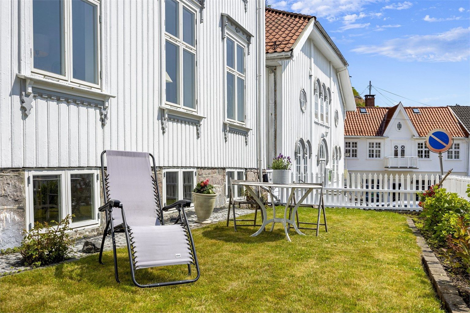 Hagen mot gaten er rammet inn av et klassisk stakittgjerde og en støttemur i naturstein.