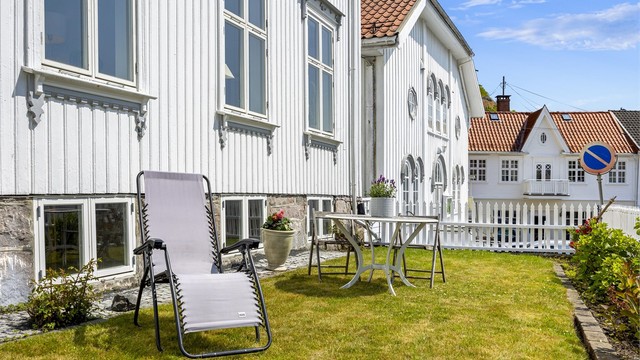 Hagen mot gaten er rammet inn av et klassisk stakittgjerde og en støttemur i naturstein.