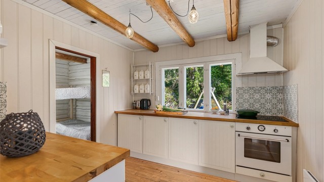 Lyst kjøkken med profilerte fronter, god oppbevaringsplass og vindu som slipper inn rikelig med dagslys