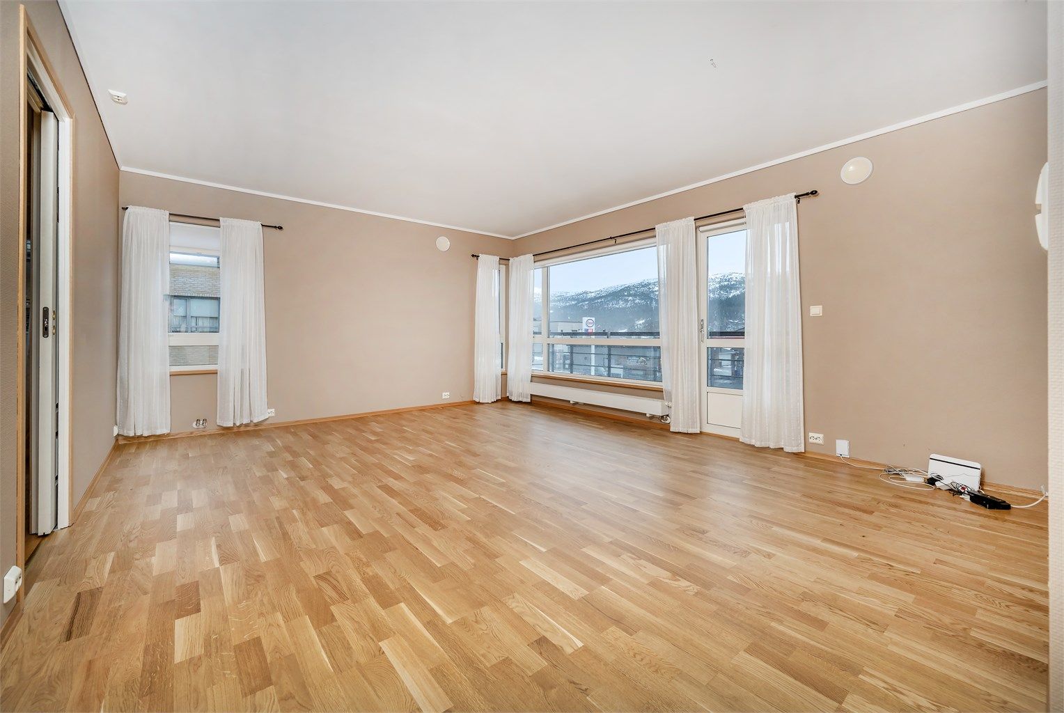 Romslig stue med store vindusflater og ny parkett lagt i 2025