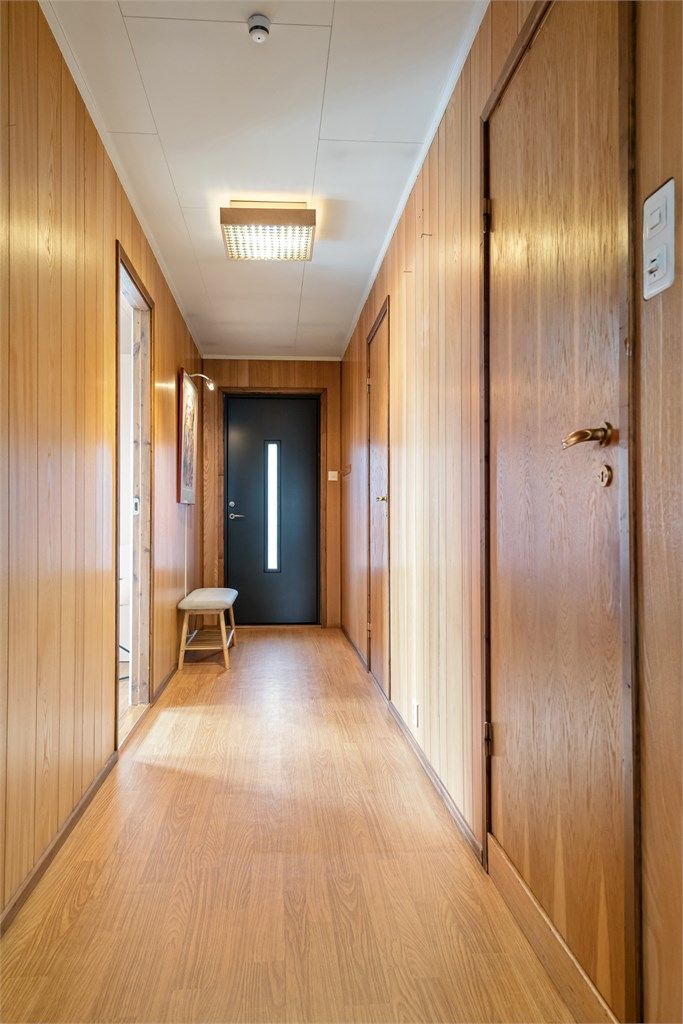 Gang med panelte vegger og adkomst til rommene i etasjen.