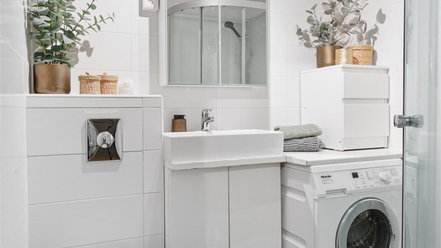 Flislagt bad med gulvvarme, vegghengt toalett, vaskemaskin og dusjkabinett.