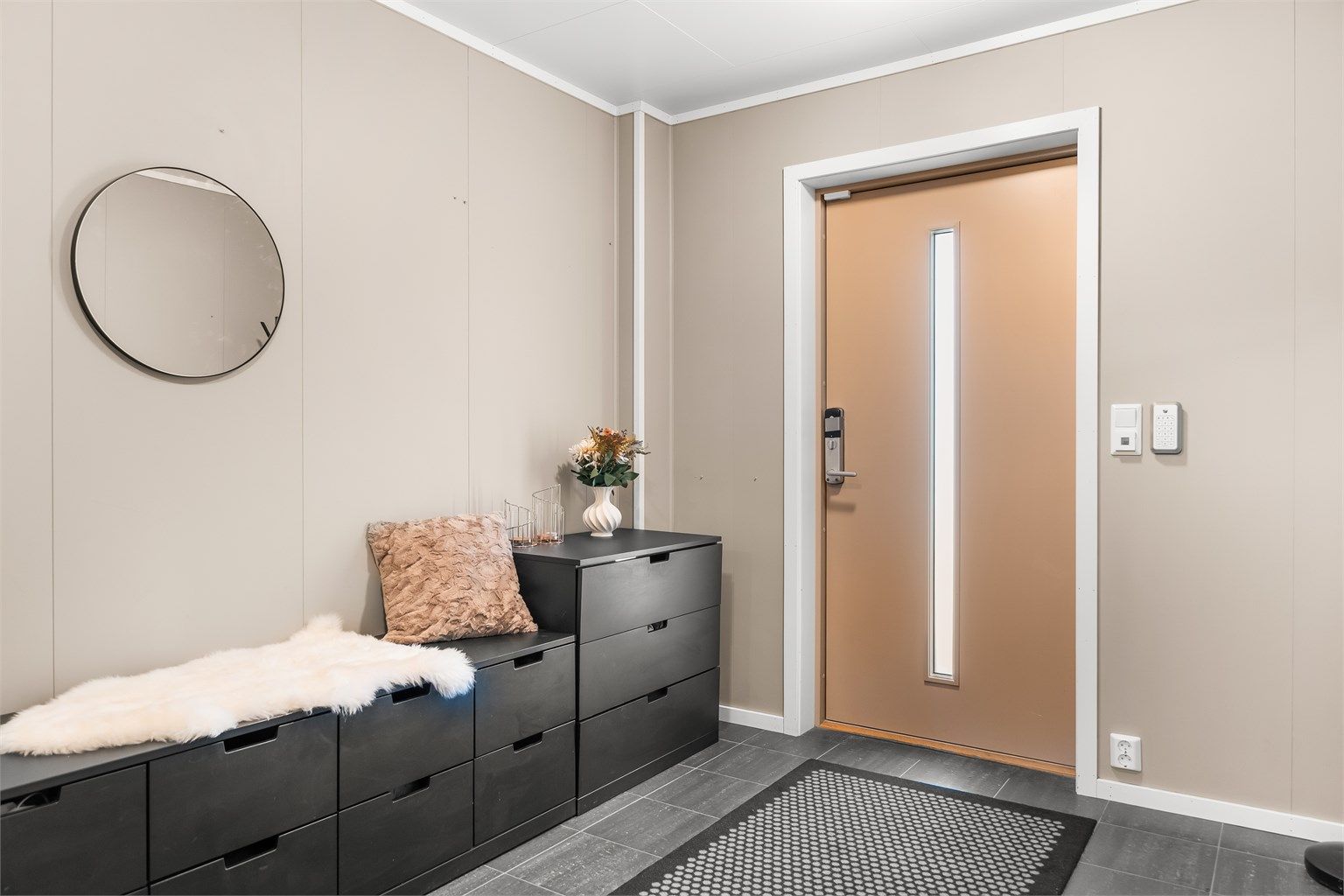 Entréen ønsker velkommen med flislagt gulv med elektrisk gulvvarme. Ytterdøren har elektronisk kodelås.