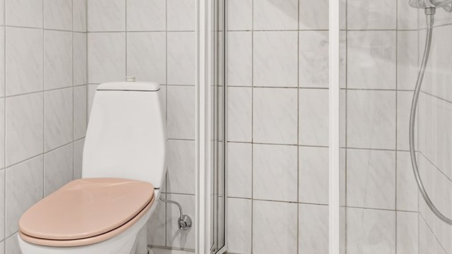 Det er vegghengt servant med armatur, speil og stikkontakt på vegg. Dusjhjørne med dører og vegghengt dusjarmatur. Baderommet har gulvstående toalett og opplegg for vaskemaskin.