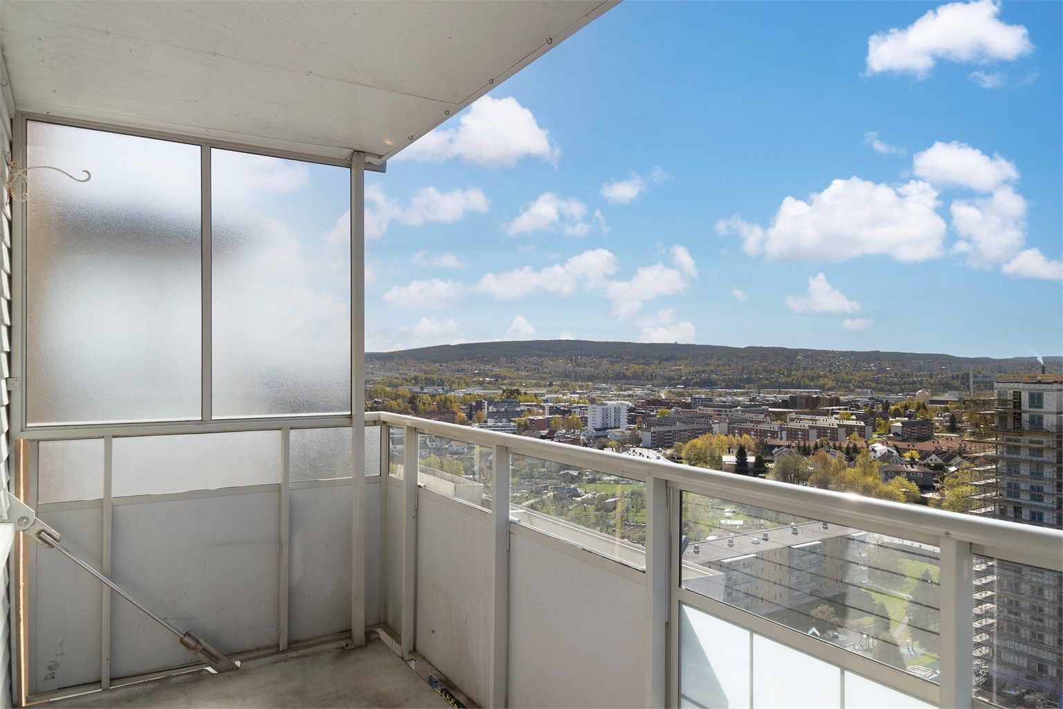 Balkongen har rekkverk i metall og glass, og et solid betongdekke.