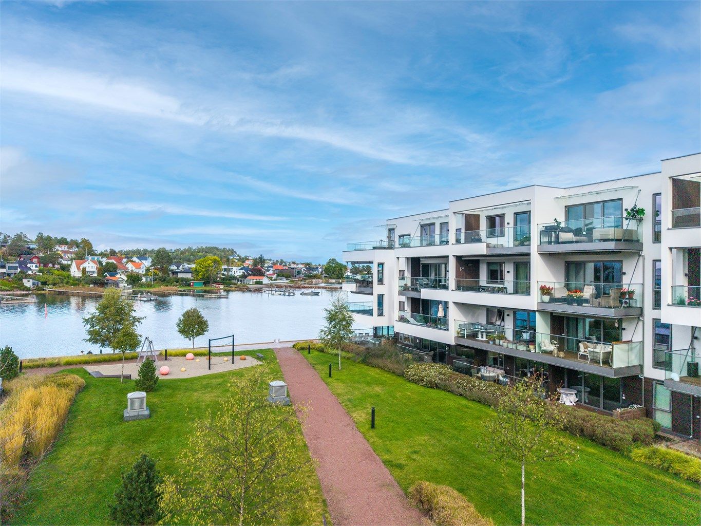 Pent opparbeidede fellesområder med plen, gangstier og beplantning.