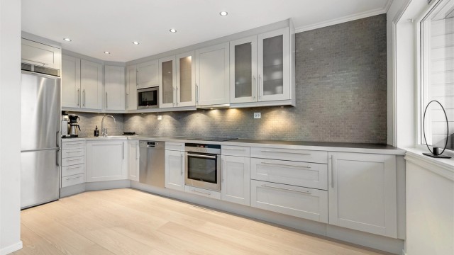 Kjøkkeninnredningen er fra Norema og har grå profilerte fronter og benkeplate av laminat med nedfelt oppvaskkum med ett-greps kjøkkenarmatur.