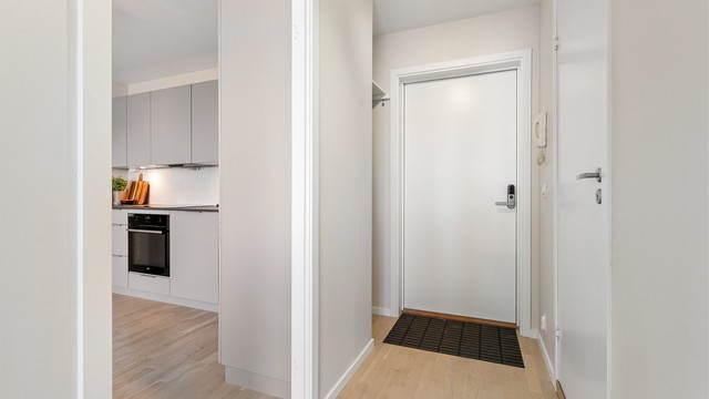 Fra entréen åpner leiligheten seg opp mot den sosiale sonen med stue og kjøkken.