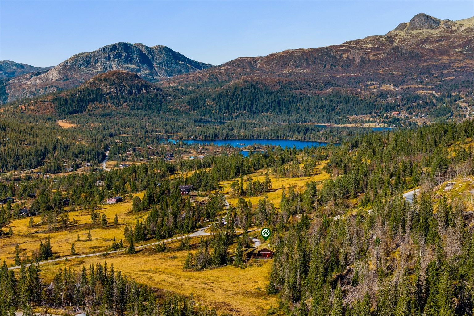 Landskapet rundt hytta er preget av fjell, skog og vann.