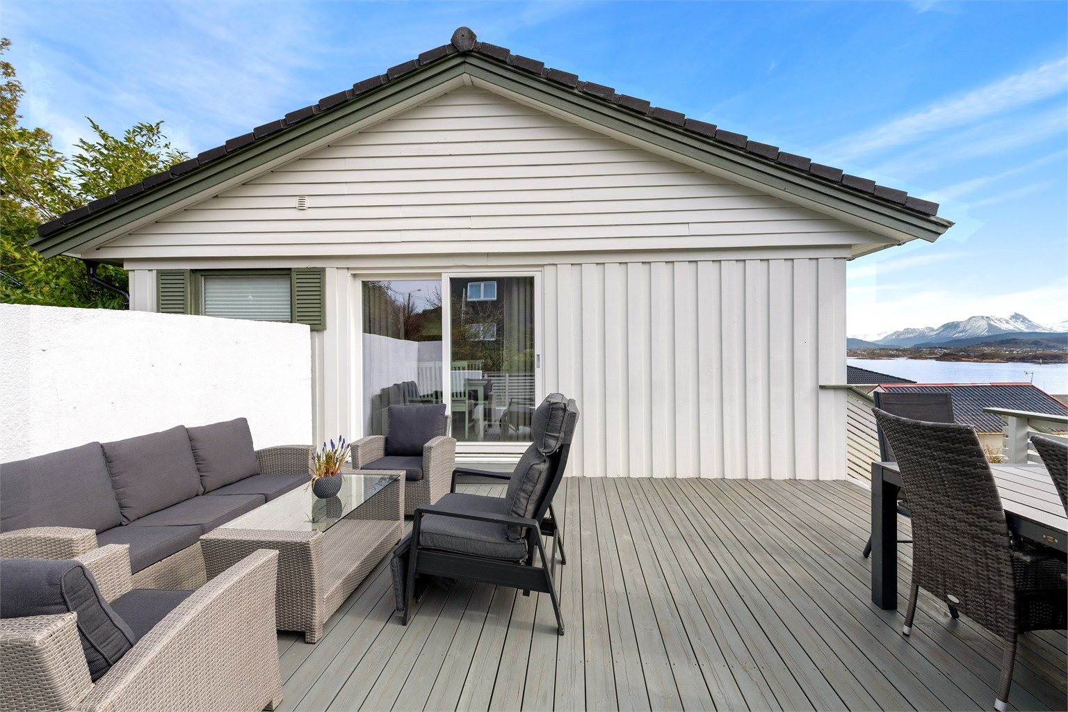 Terrassen er delvis skjermet av en pusset murvegg mot adkomstvei, som skaper en lun og privat sone.