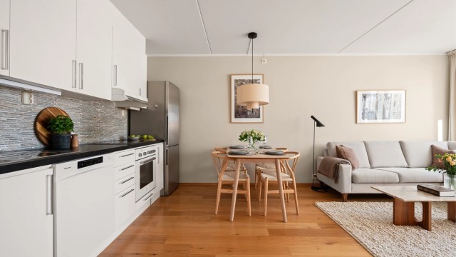 Kjøkkeninnredningen har glatte fronter, laminat benkeplate med nedfelt vask, og er utstyrt med integrert platetopp og stekeovn.