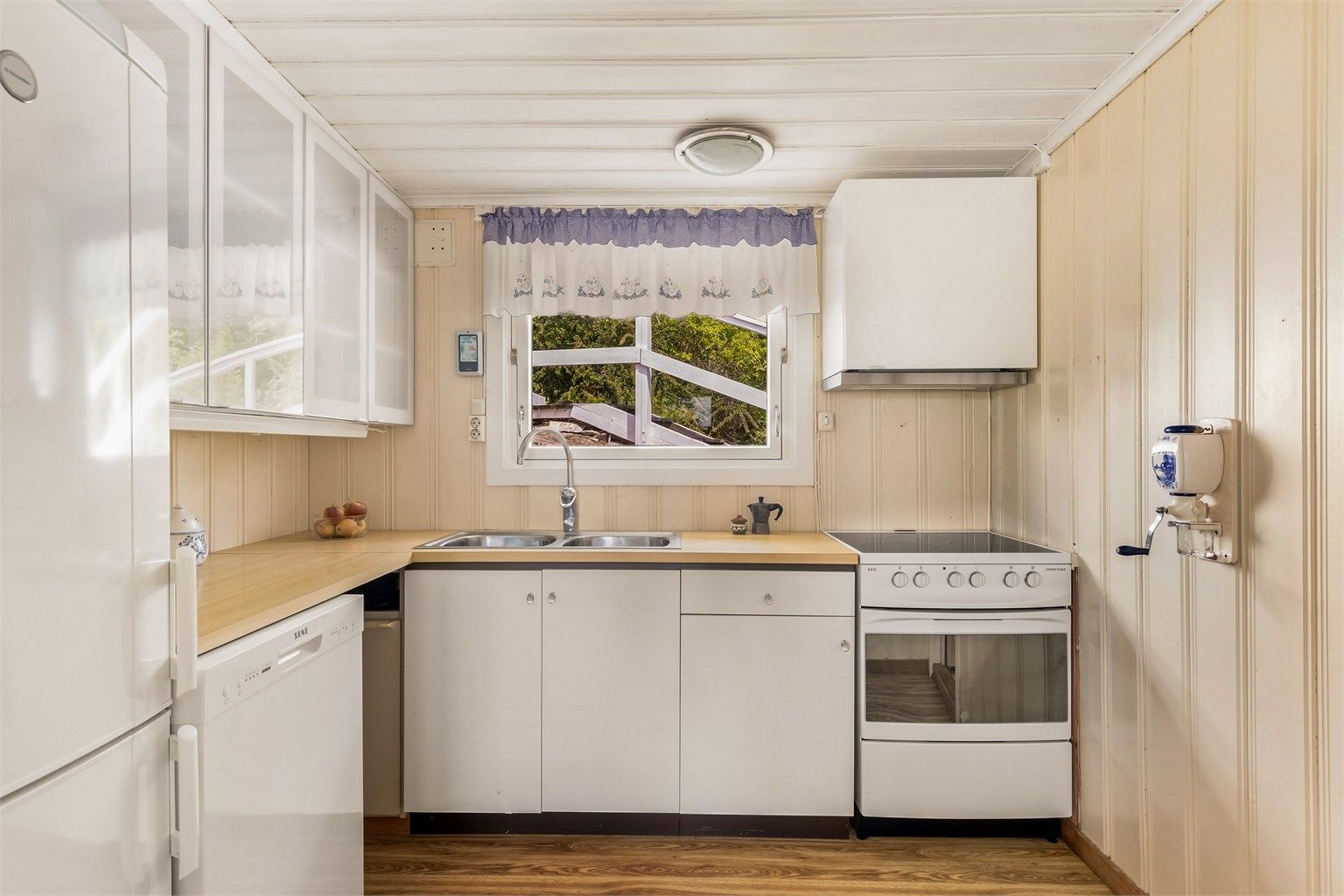 Kjøkken med enkel innredning med slette fronter, ventilator, stålvask. Komfyr, oppvaskmaskin, kjøl- og fryseskap medfølger i handelen.