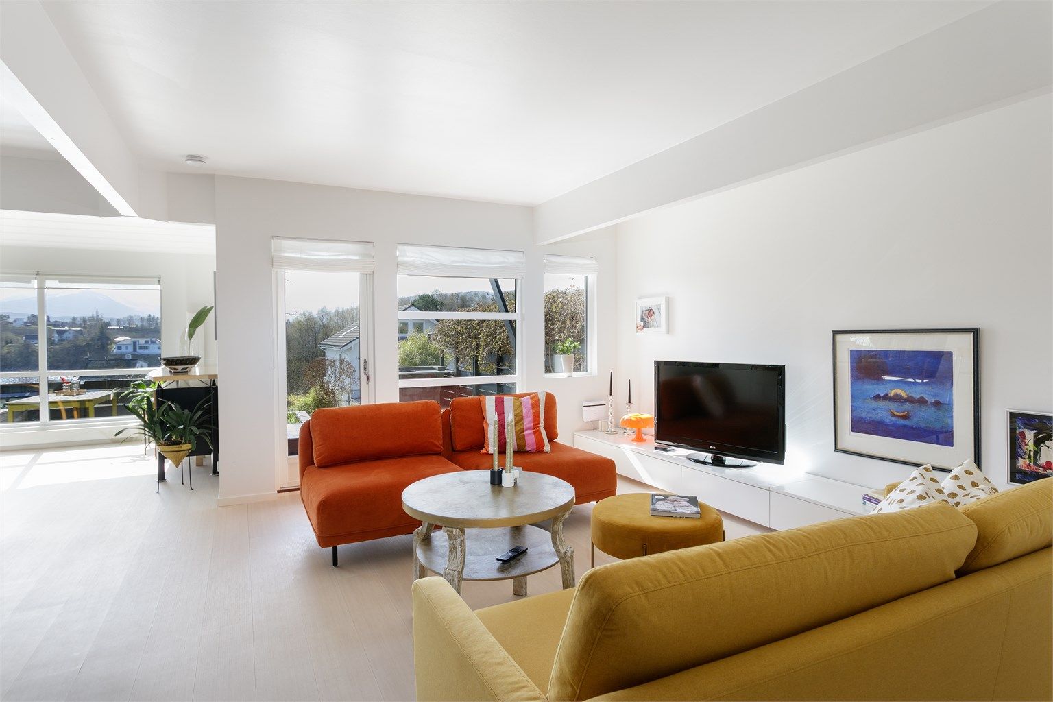 Stue i hovedetasjen med lyse overflater og godt med naturlig lysinnslipp fra sydvendte vinduer