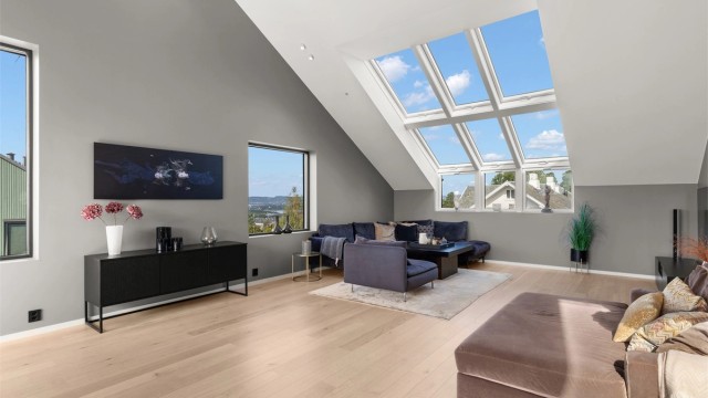 Stuen er boligens naturlige midtpunkt, med imponerende takhøyde og store vindusflater som gir et særegent lysinnslipp og en umiddelbar wow-faktor.