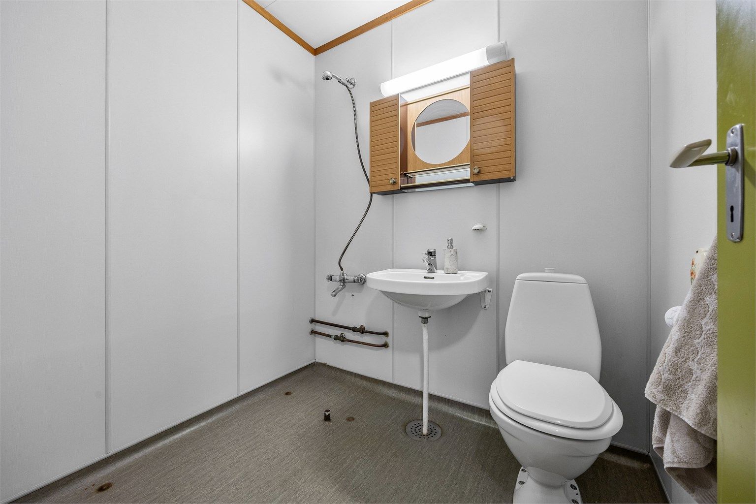 Badet er utstyrt med toalett, servant og dusjløsning.