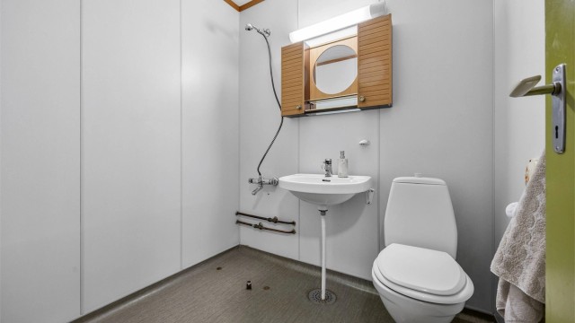 Badet er utstyrt med toalett, servant og dusjløsning.