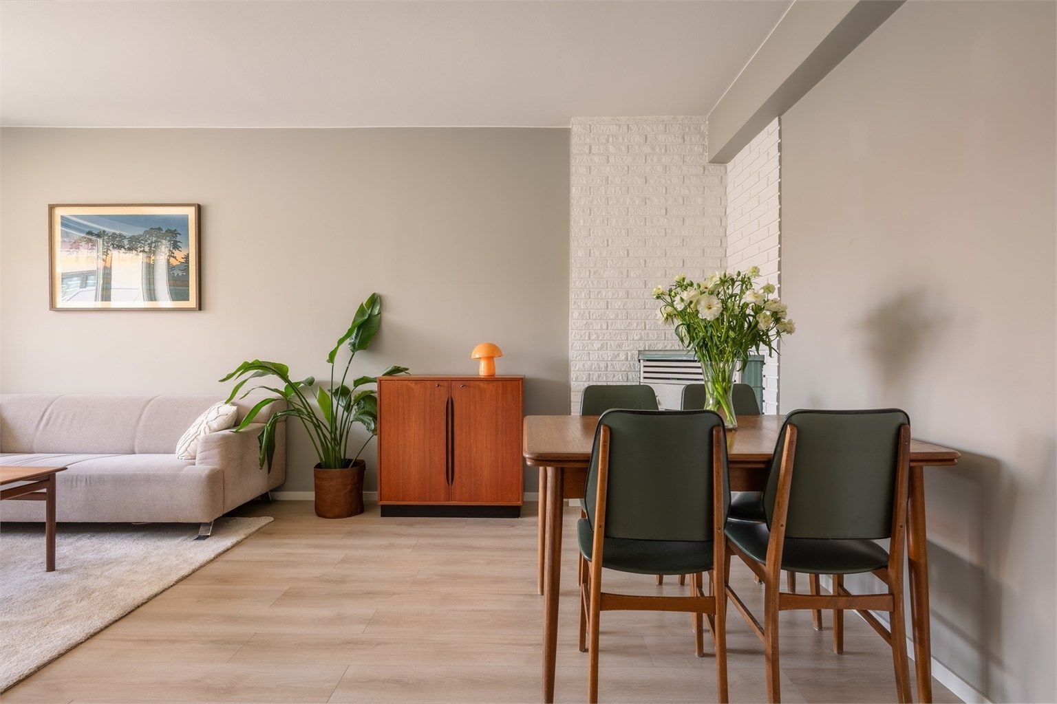 Stuen er malt i lyse toner med gjennomgående en-stavs laminat på gulv.