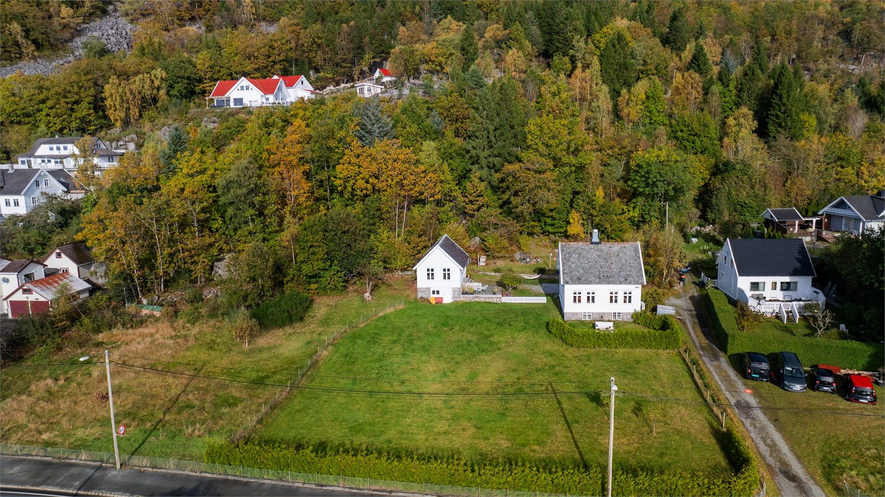 Tomten strekker seg over 5,6 mål med store grøntarealer og skogkledd bakside.