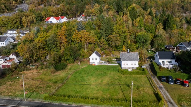 Tomten strekker seg over 5,6 mål med store grøntarealer og skogkledd bakside.