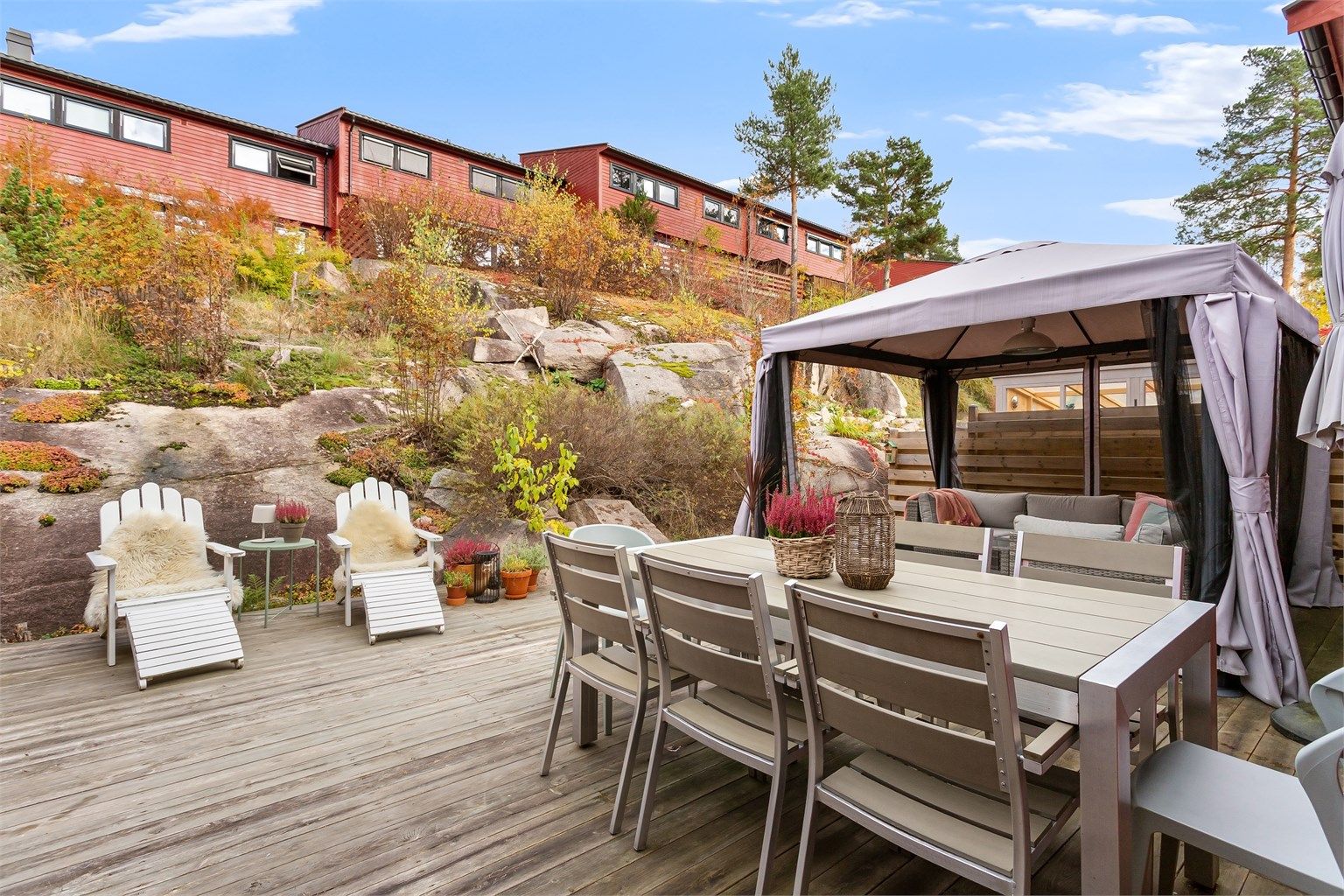 Utgang fra kjøkkenet til terrasseplatting på 43 kvm med god plass utemøbler. Paviljong medfølger.  