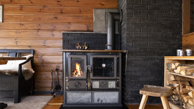 Klassisk vedkomfyr med bakerovn og synlige flammer gir god varme til stuen.