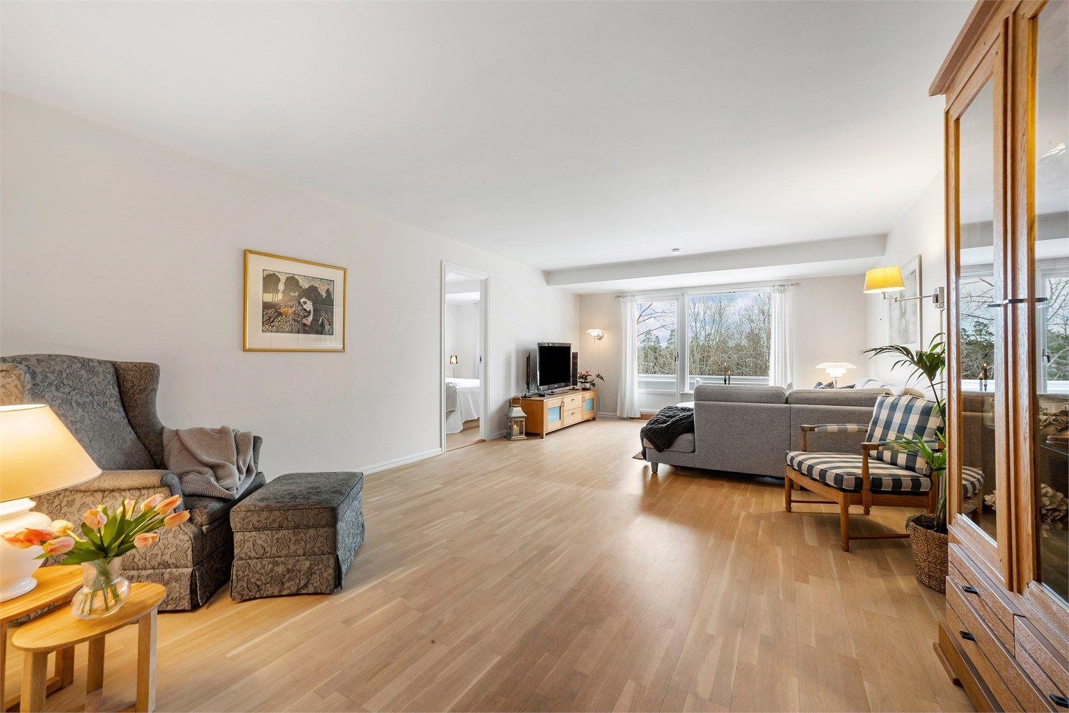 Stor og lys stue med parkettgulv og hvitmalte flater. 