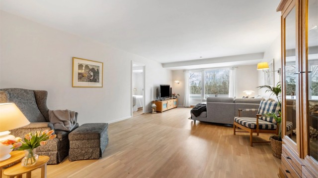 Stor og lys stue med parkettgulv og hvitmalte flater.