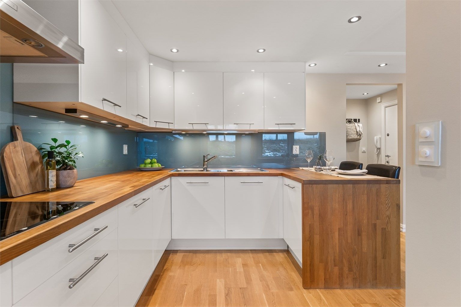 Delvis åpen kjøkkenløsning med innredning fra 2010, benkeplate i tre og integrerte hvitevarer.