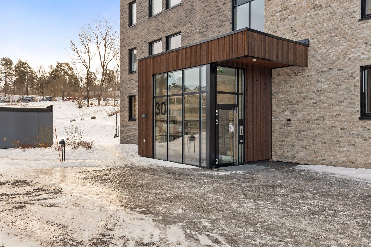 Inngangsparti med trepanel og teglsteinsfasade.