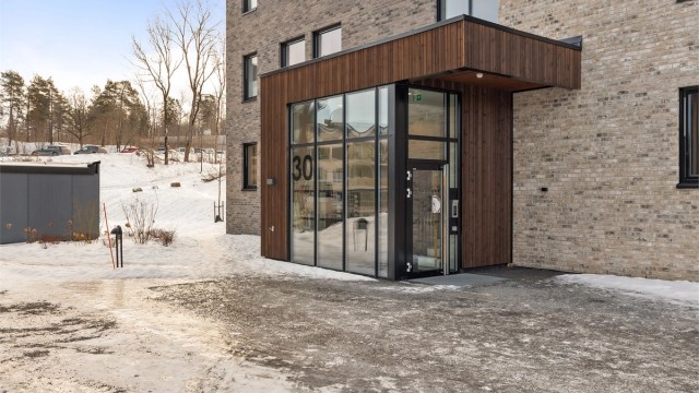 Inngangsparti med trepanel og teglsteinsfasade.