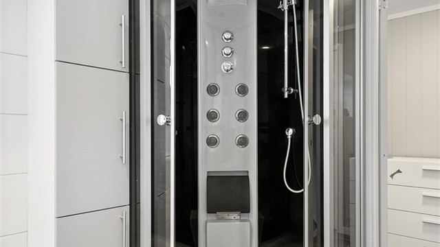 Dusjkabinett med spafunksjon og tilhørende oppbevaringsskap på badet i underetasjen.