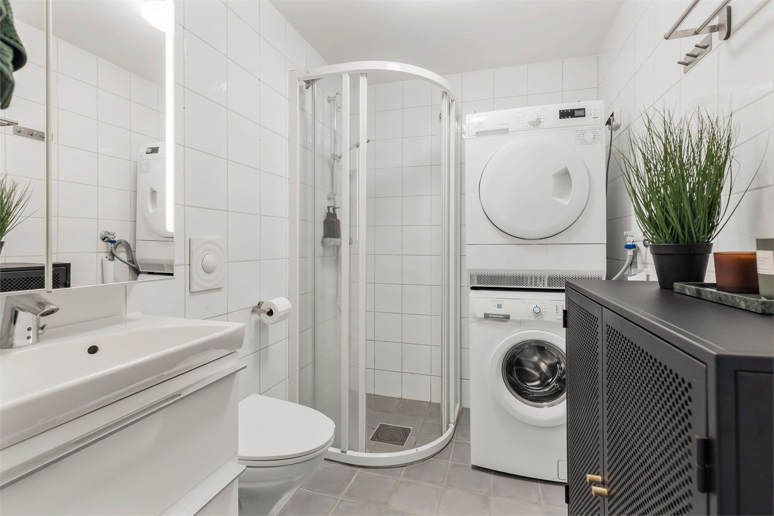 Flislagt bad med dusjhjørne som har skyvedørsramme