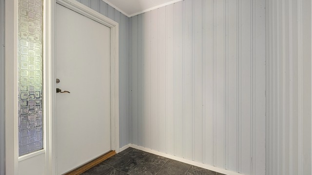 Entré med laminatgulv og malt panel på veggene.