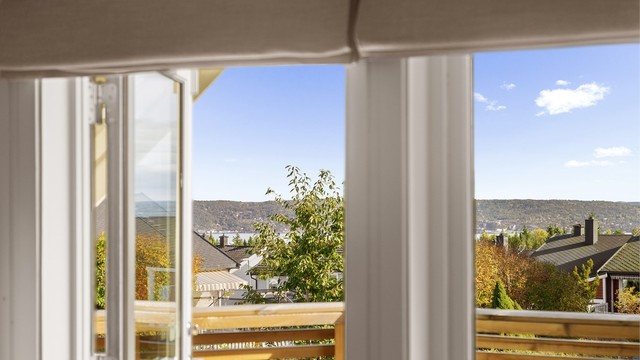Fra balkongen er det åpent utsyn mot fjorden og de grønne omgivelsene.