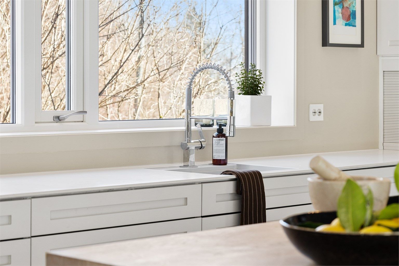 Åpen kjøkkenløsning mot stue. Kjøkkeninnredning med slette fronter fra HTH. Benkeplate av tre og laminat. Nedfelt oppvaskkum med ett-greps armatur. Stikkontakter på vegg over kjøkkenbenk.