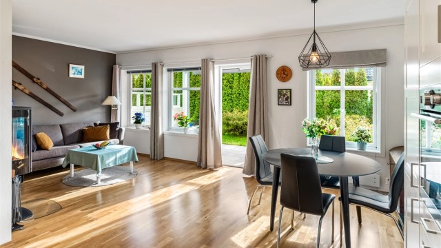 Stuen har god plass til både sofagruppe og spisebord, med peisovn som gir lun varme.