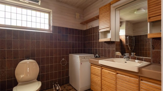 Pent delvis flislagt bad med opplegg for vaskemaskin.