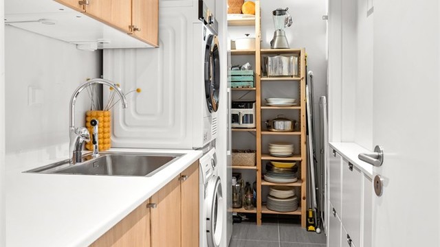 Moderne vaskerom med vegghengt innredning med overskap og underskap - opplegg for vaskemaskin og tørketrommel og praktisk tilknytning til innvendig bod.