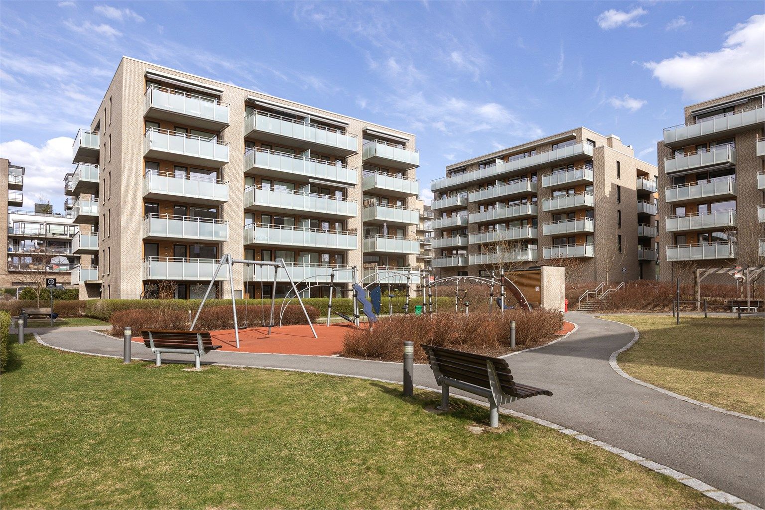 Gårdstun med lekeplass og sittebenker.