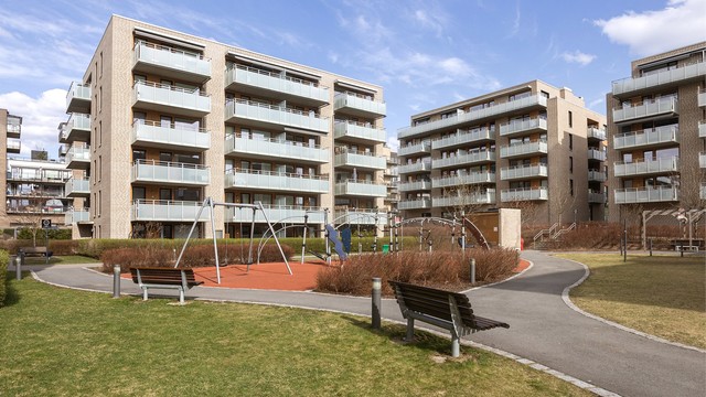 Gårdstun med lekeplass og sittebenker.