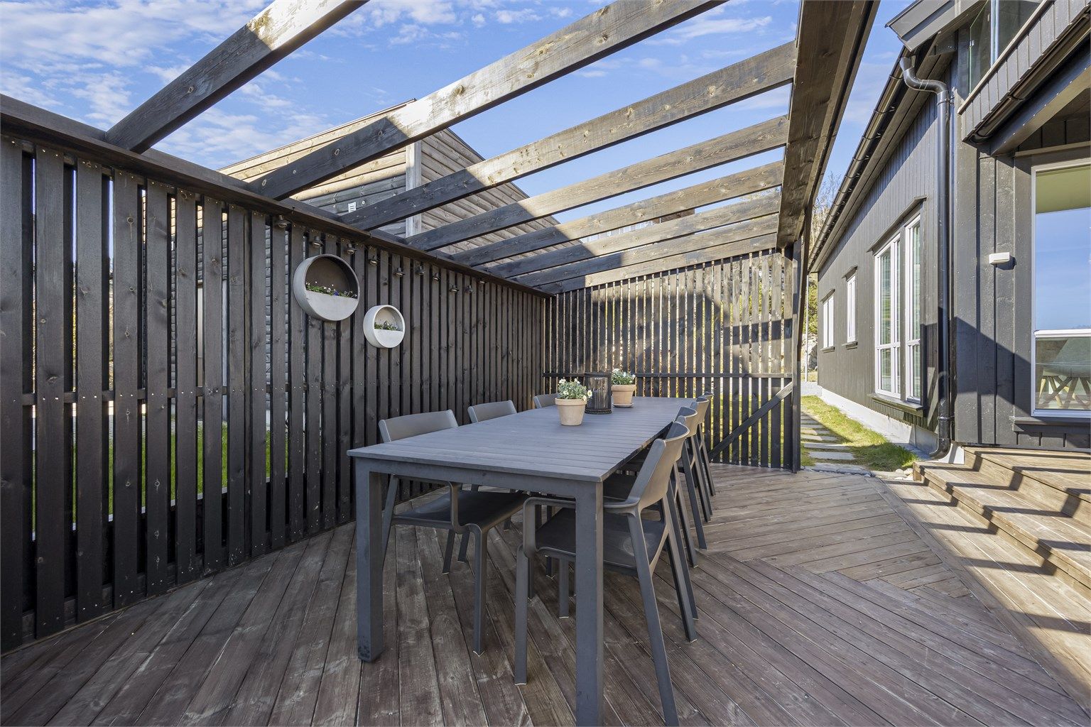 Terrassen er bygget i tre i fiskebeinsstil under pergolaen.