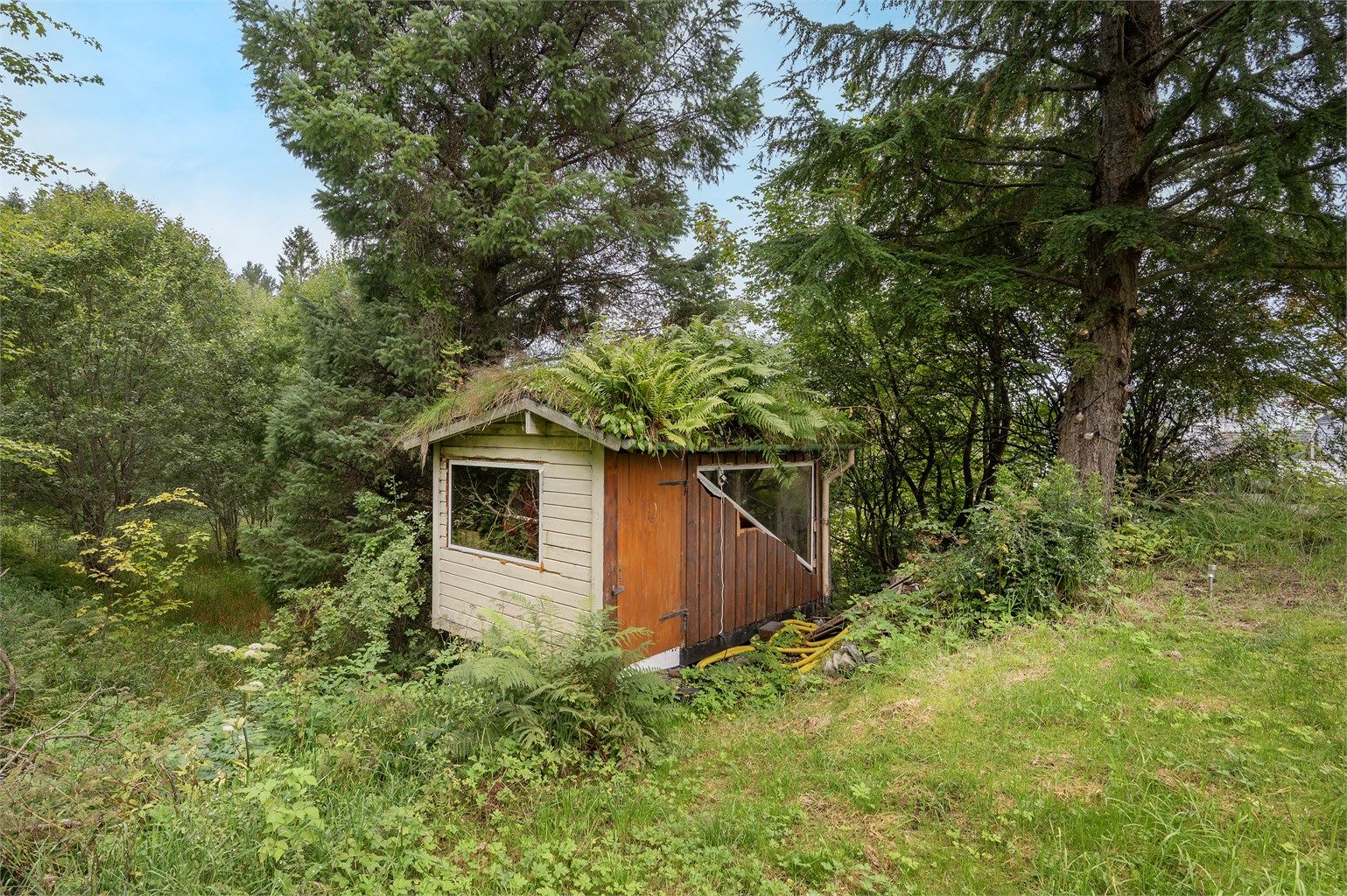 Frittstående bod med torvtak gir ekstra lagringsplass på eiendommen.