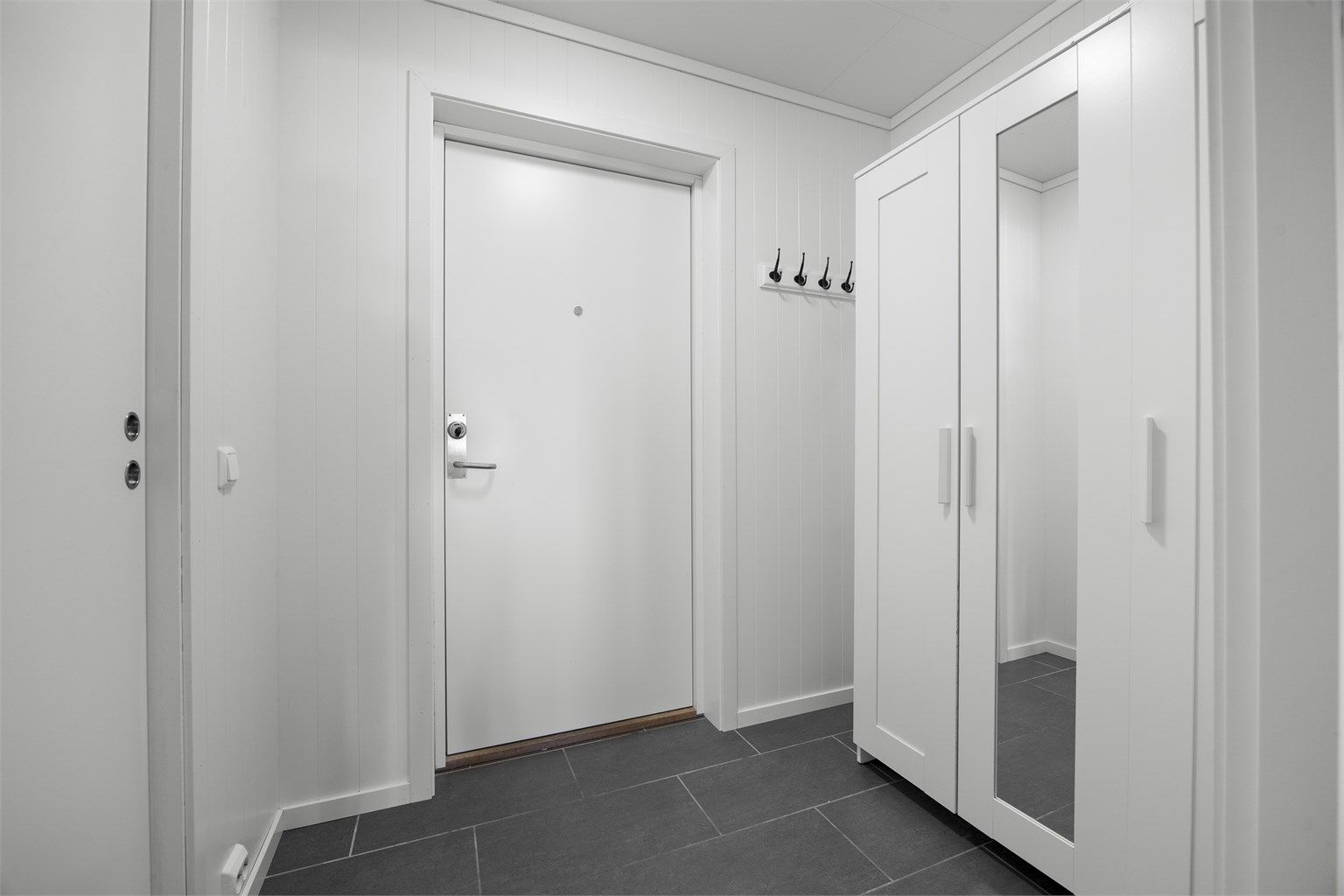 Entré med flislagt gulv og plass til garderobeløsning.