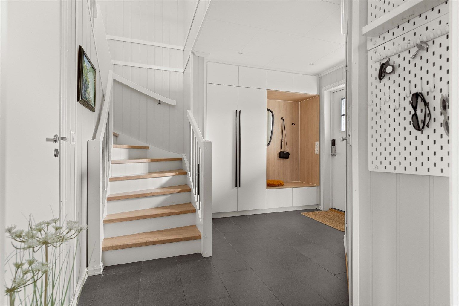 Her blir du møtt med en romslig entré, som gir et godt førsteinntrykk. Den skreddersydde garderoben gir både funksjonalitet og et stilrent uttrykk. 