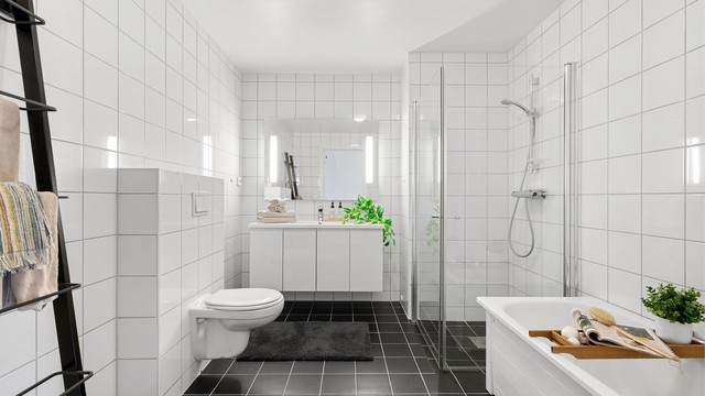 Bad II er av lik design som bad I og har dusj med innfellbare dører, badekar, vegghengt toalett og servant med oppbevaringsplass.. Stort speil med innfelt lys på vegg. Det er mørke fliser på gulv og lyse på vegg.
