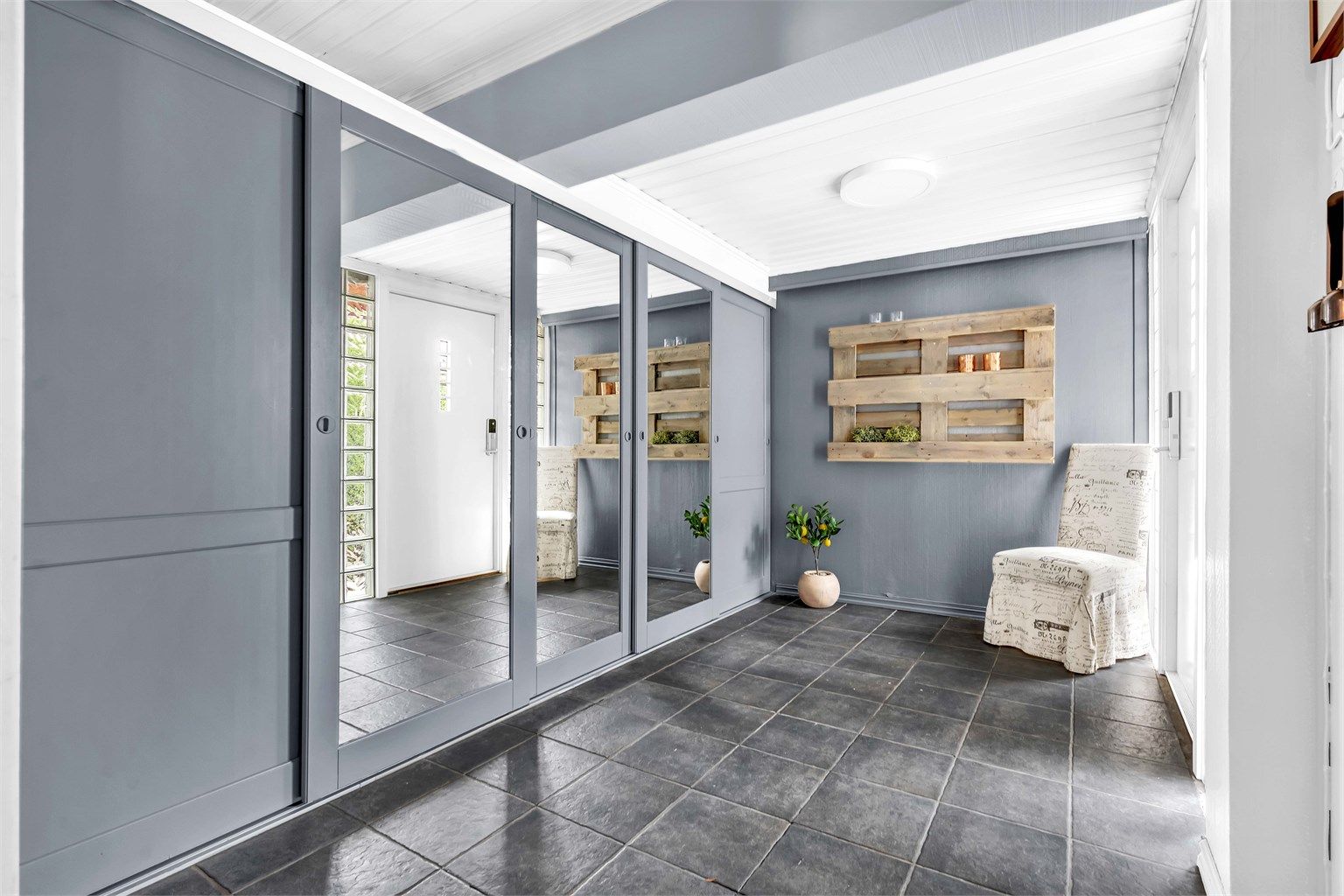 Innbydende og romslig entré med gode oppbevaringsmuligheter til yttertøyet i skyvedørsgarderobe.