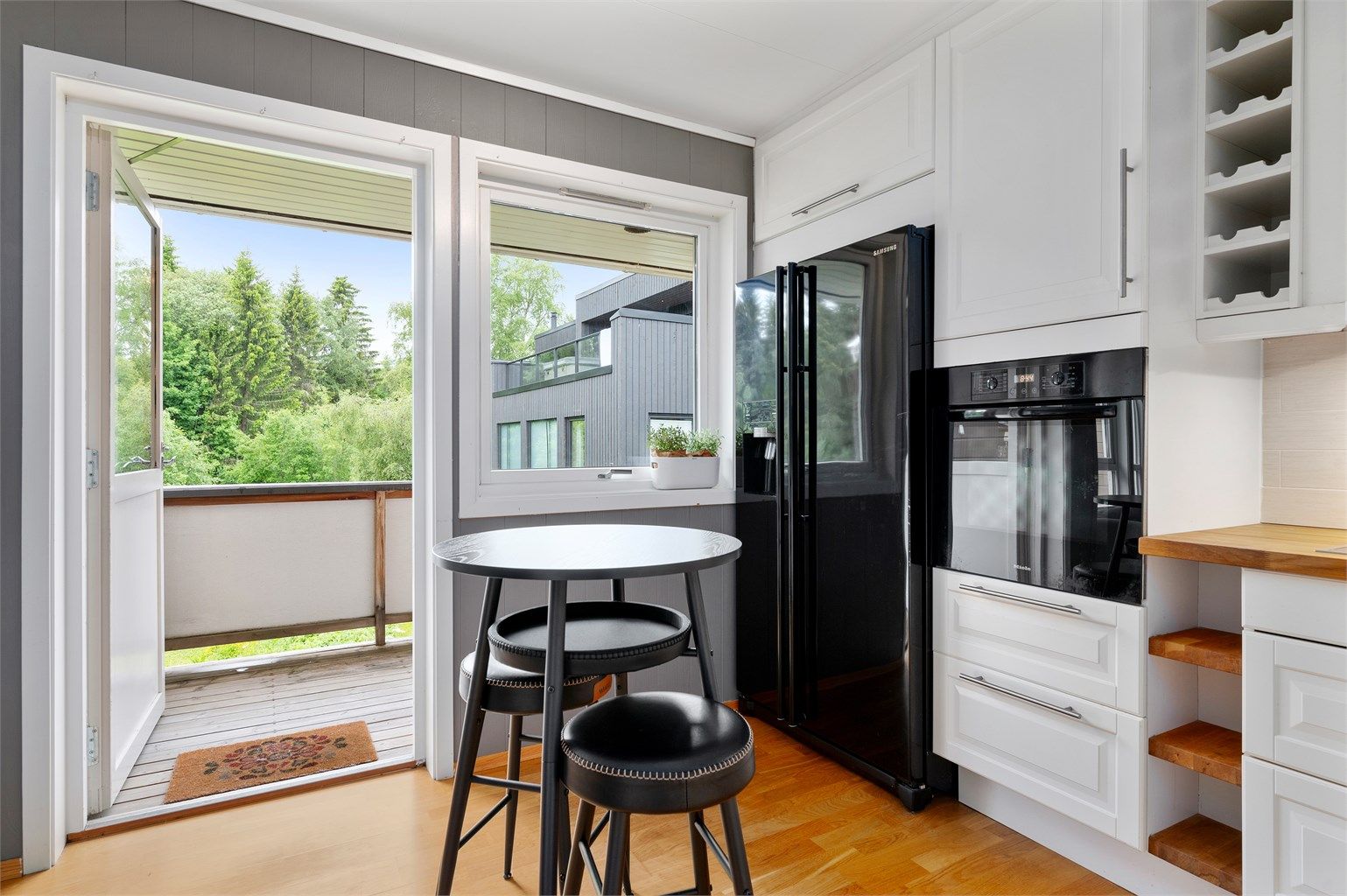 Kjøkkenet har praktisk direkte utgang til balkongen – en løsning som gir god kontakt mellom inne- og uterom. Kjøleskapet medfølger salget.