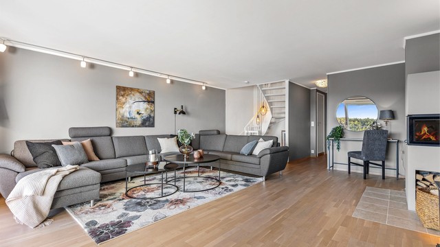 Store vindusflater slipper inn rikelig med dagslys inn i stuen. Det er peis i stuen.
